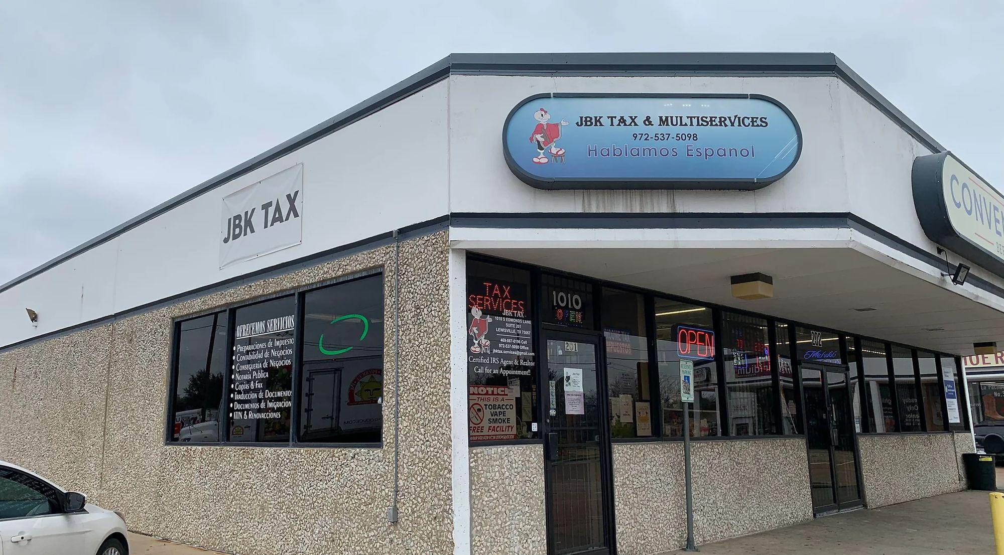 The JBK Tax & Multy Services office at 1010 S Edmonds Lane in Lewisville, a white corner building with a blue sign that says Hablamos español.