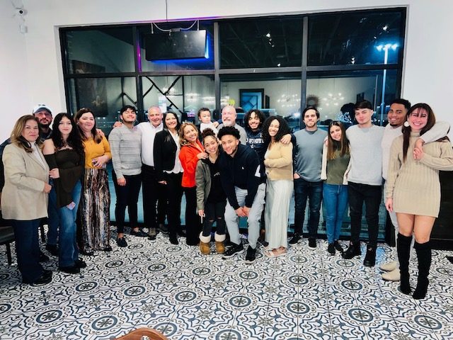 A large group posing together at an evening gathering connected to JBK Tax.